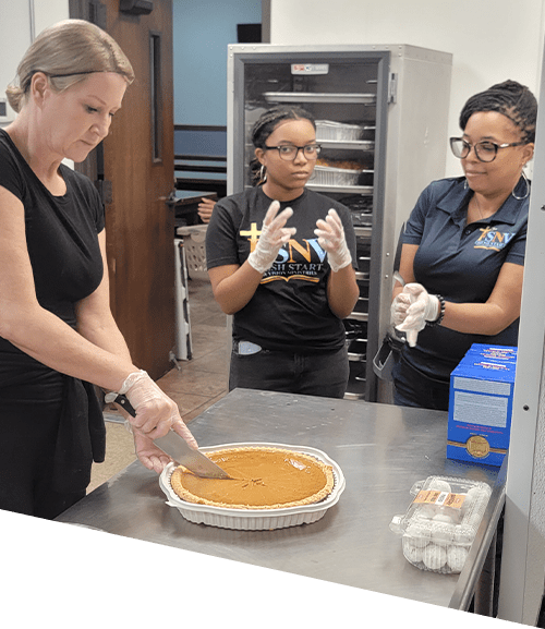 Three women in a kitchen preparing food.