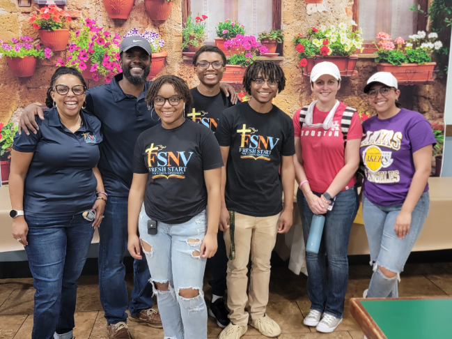 A group of people standing in front of flowers.