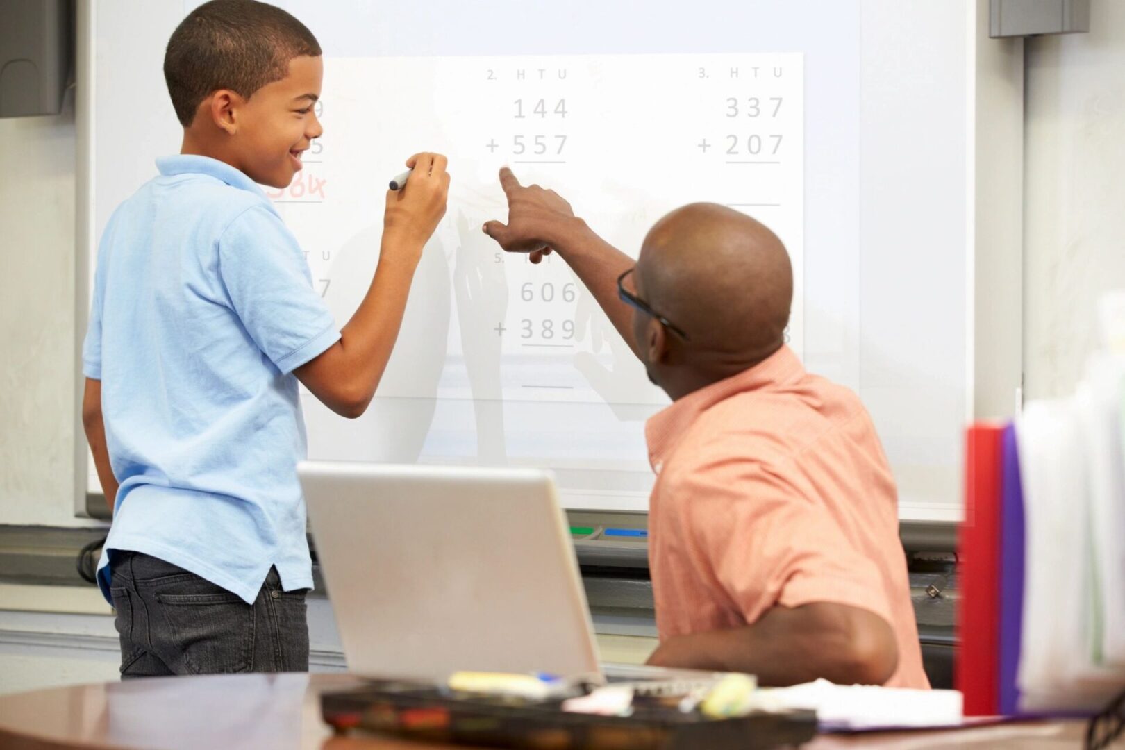 A man and boy pointing at a whiteboard